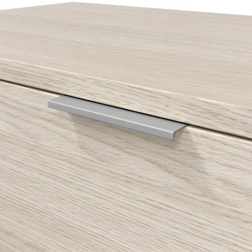 Tirador metálico plateado de perfil rectangular sobre cajón de madera clara y textura veteada