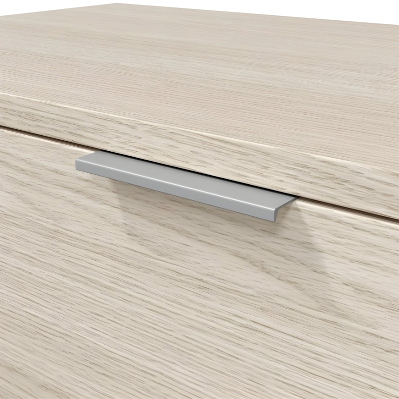 Tirador metálico plateado de perfil rectangular sobre cajón de madera clara y textura veteada