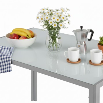 Mesa de comedor blanca con tapa de cristal y patas metálicas grises en ambiente decorado