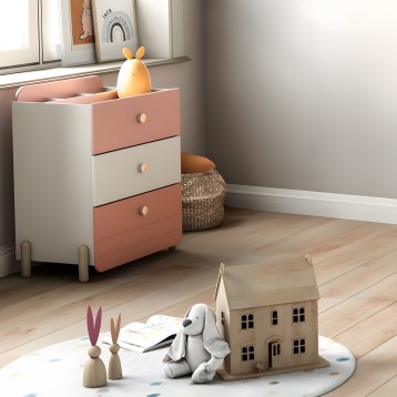 Cómoda infantil con tres cajones rosa y blanco y patas de madera en dormitorio infantil