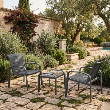 Conjunto de jardín con dos sillones y mesa auxiliar de metal gris y textileno en patio mediterráneo
