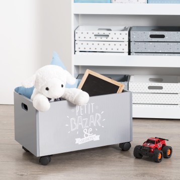 Baúl infantil gris con ruedas y asas contiene juguetes y peluche blanco en dormitorio