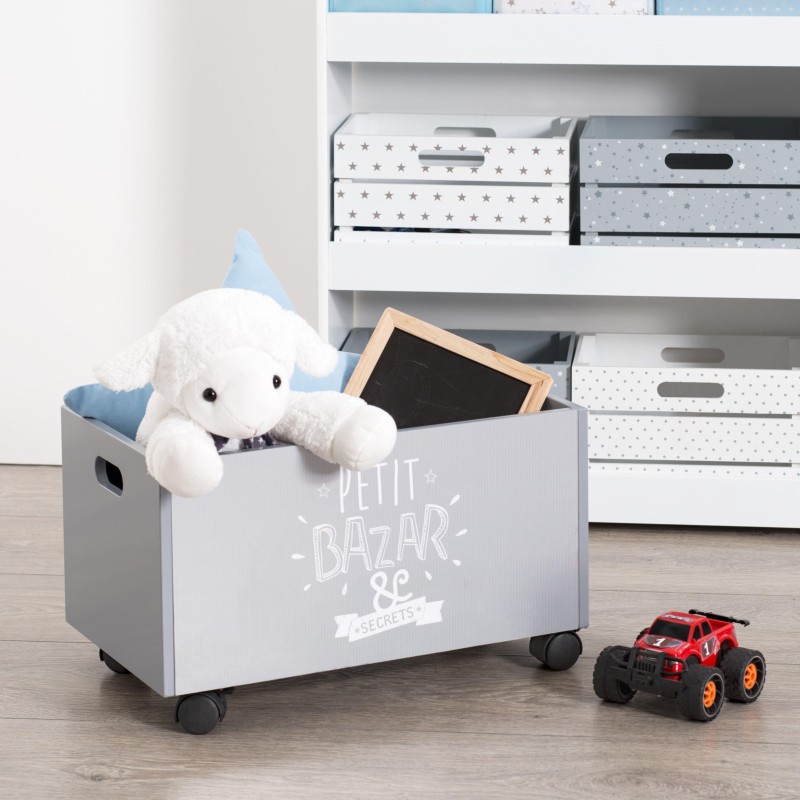 Baúl infantil gris con ruedas y asas contiene juguetes y peluche blanco en dormitorio