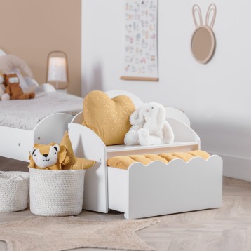 Baúl infantil blanco con formas onduladas y almohadas beige y blancas en dormitorio infantil