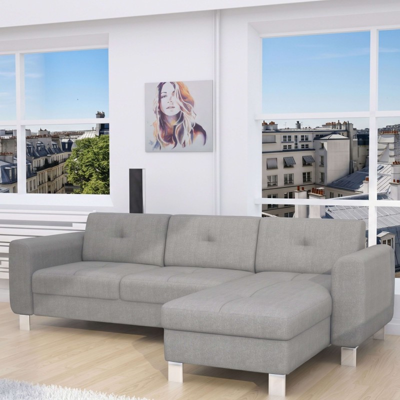 Sofá seccional gris claro con chaise longue y patas metálicas en ambiente luminoso con vistas urbanas