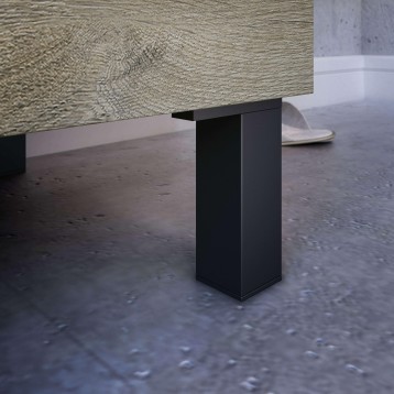 Mesa con tablero texturizado en tonos beige y pata central de metal negro en ambiente de hormigón