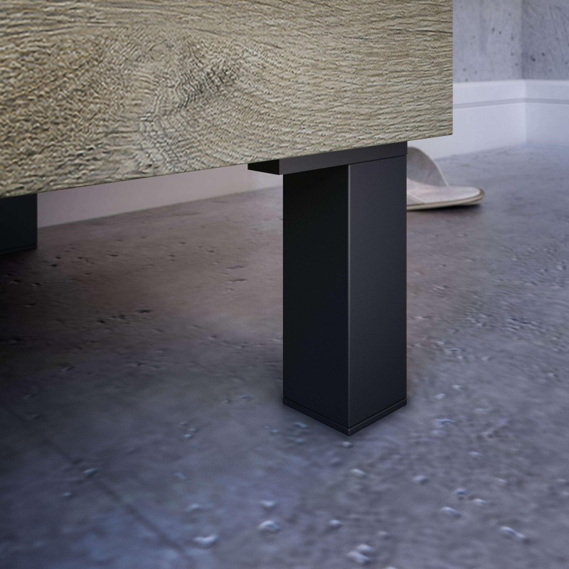 Mesa con tablero texturizado en tonos beige y pata central de metal negro en ambiente de hormigón