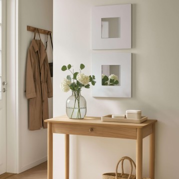 Consola de madera clara con cajón y floreros decorativos en ambiente de recibidor
