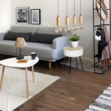 Salón moderno con sofá gris y cojines negros junto a mesita redonda blanca y taburete con tapa de madera