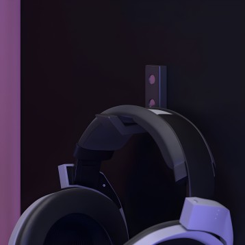 Auriculares inalámbricos negros con detalles morados y caja de almacenamiento vertical detrás