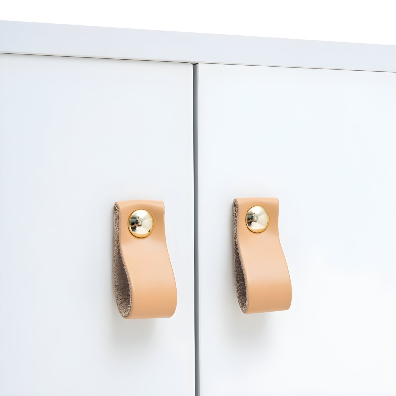 Detalle de tiradores de cuero natural melocotón con acabado dorado en puertas de mueble blanco