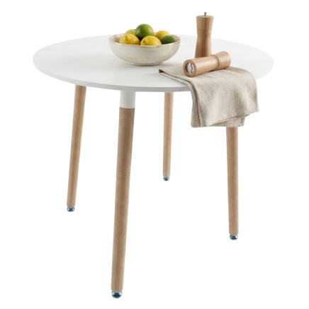 Mesa redonda blanca con patas de madera natural y accesorios de cocina