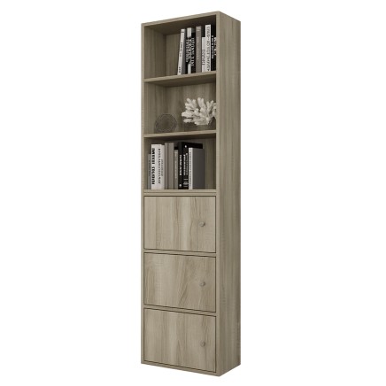 Estantería vertical de madera clara con tres estantes abiertos y tres puertas inferiores. Decorada con libros y adornos blancos.