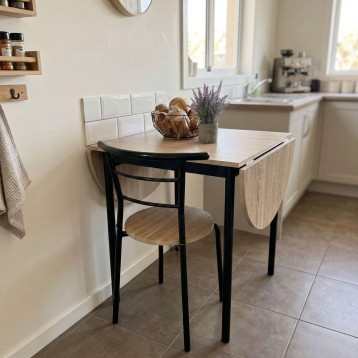 Mesa redonda extensible con tablero en madera clara y patas negras junto a silla de madera y estructura negra en cocina