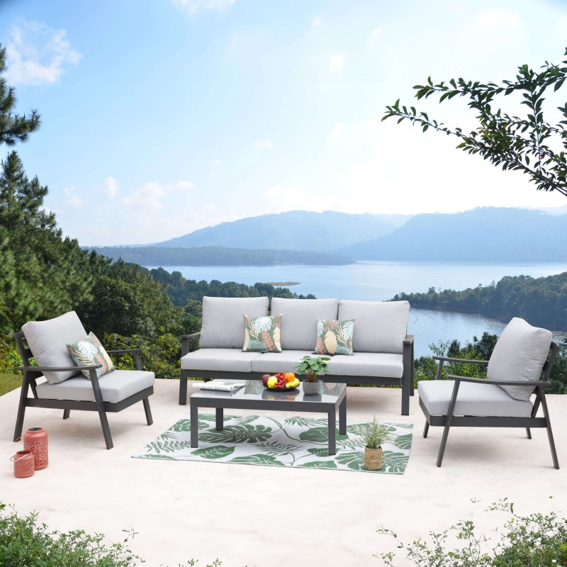 Conjunto de sofá y sillones de exterior con estructura negra y cojines grises y mesa de centro en terraza frente al lago