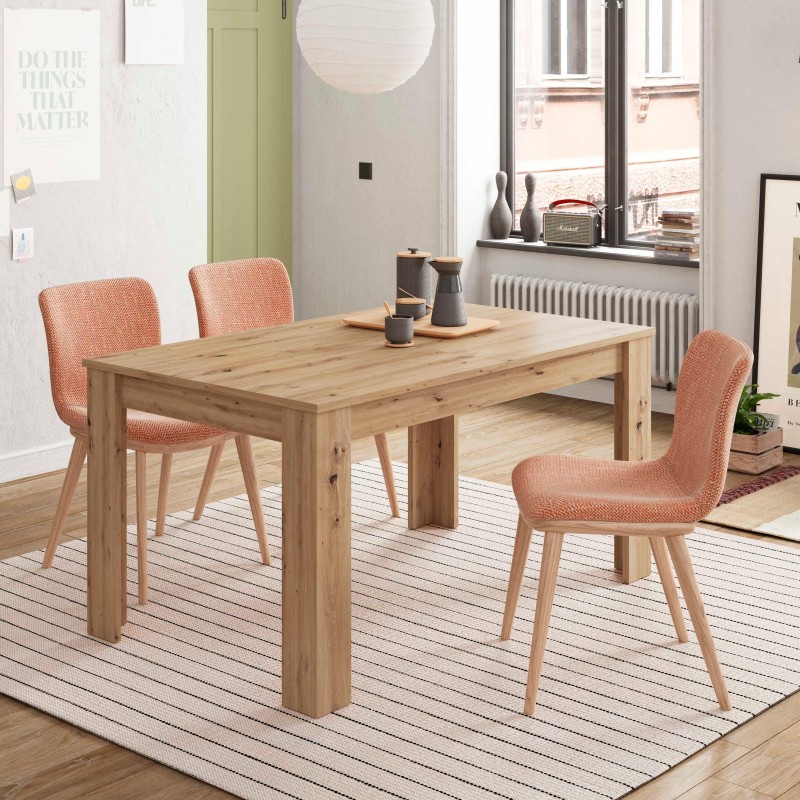 Comedor con mesa de madera clara y sillas tapizadas en tela naranja en ambiente luminoso junto a ventana