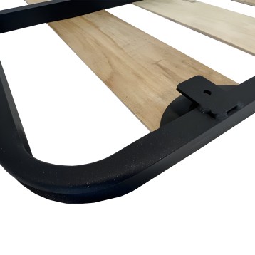 Cama con estructura negra y tablero de madera clara detalle de pata y mecanismo de soporte