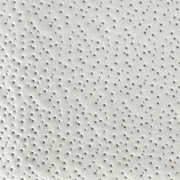 Detalle de tapizado en tela beige con textura de relieve puntillado y acabado acolchado