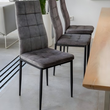 Silla de comedor tapizada en gris oscuro con respaldo acolchado y estructura metálica negra