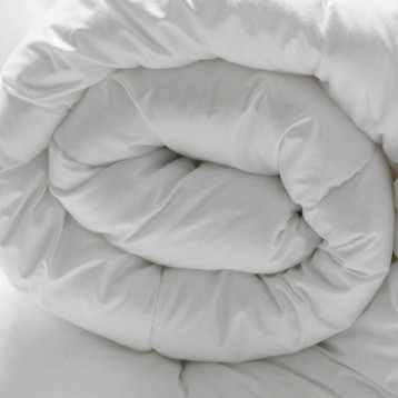 Detalle de ropa de cama blanca enrollada y plegada mostrando la textura del tejido suave