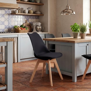Silla de comedor con asiento negro y patas de madera clara en cocina de estilo nórdico