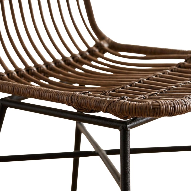 Detalle de silla colgante con estructura metálica negra y asiento tejido en ratán marrón con respaldo acanalado