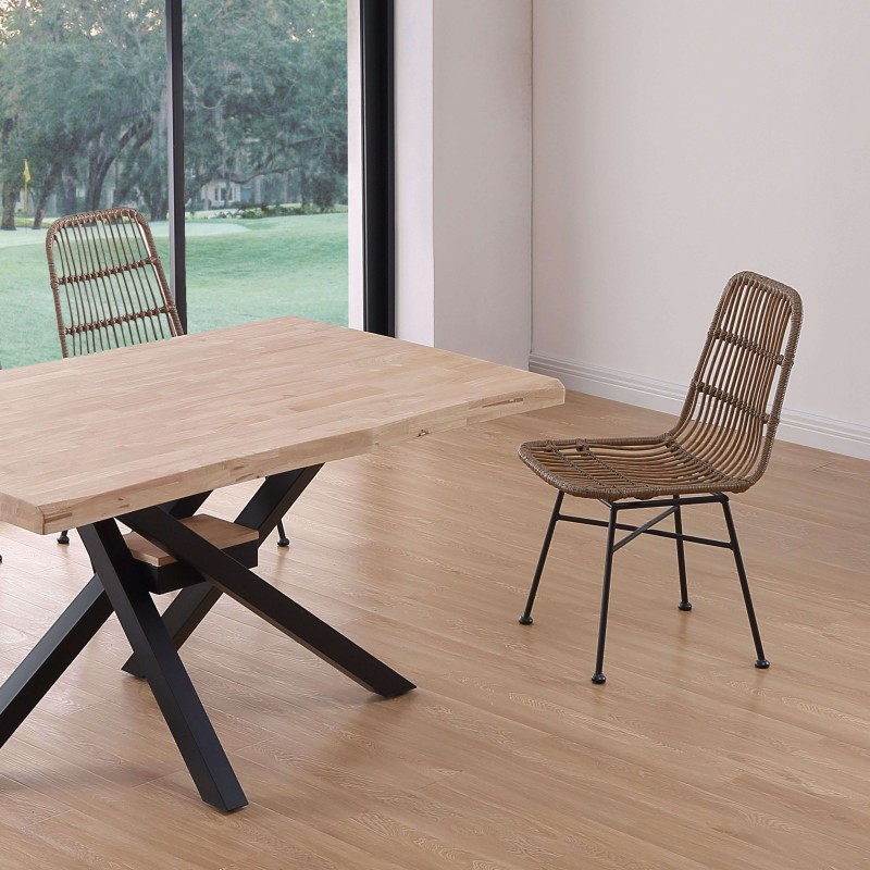 Silla de ratán marrón con estructura metálica negra en ambiente de comedor junto a mesa de madera y base X negro