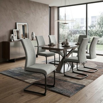 Comedor moderno con mesa negra y sillas grises tapizadas en ambiente de vivienda junto a ventanal