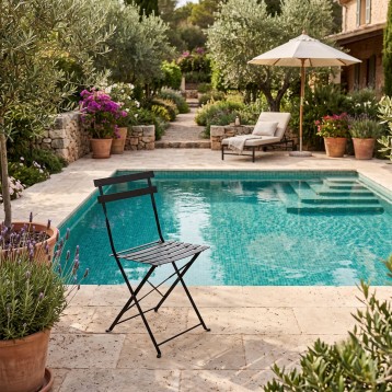 Silla plegable de metal negro junto a piscina en ambiente de jardín mediterráneo