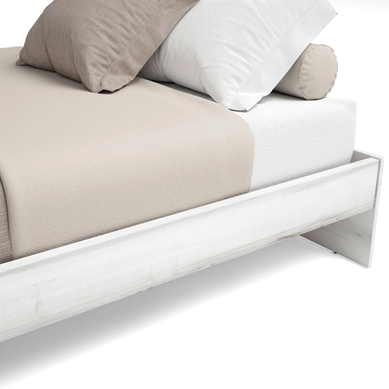 Cama blanca con colchón beige y almohadas en tonos neutros de tela textil vista frontal