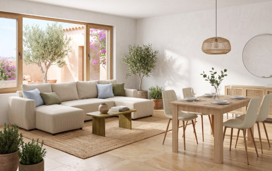 Sofá rinconera de pana beige con cojines azules y verdes junto a mesa de comedor de madera en salón luminoso